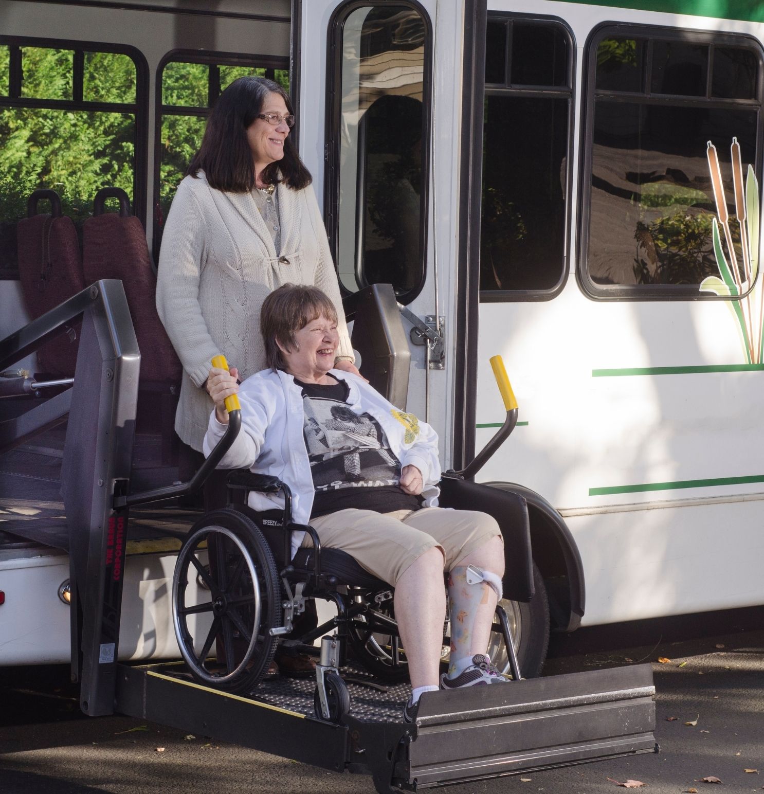 an elderly woman who is physically disabled being assisted out of a public bus