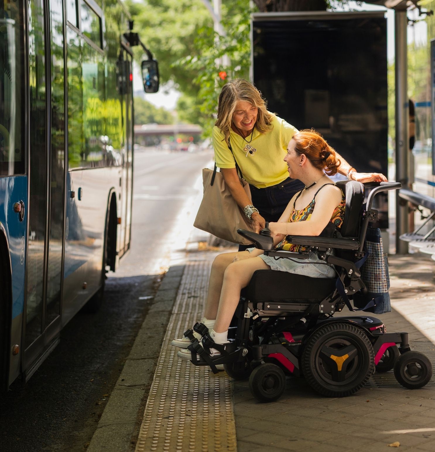 woman helping a disabled woman get on the bus
